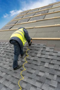 A roofing contractor installing shingles on roof